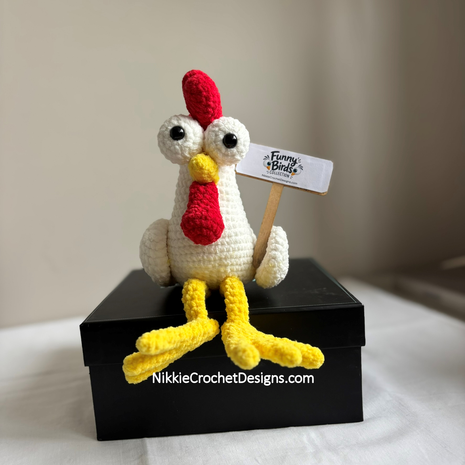 Cheeky Chicken on a box with its yellow legs dangling, holding a Funny Birds sign